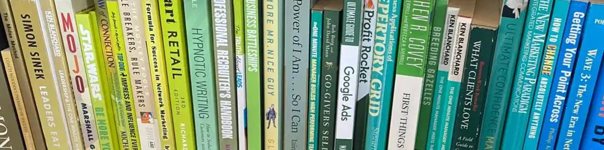 Banner image of a bookshelf with books in a gold colour on the left, transitioning through green to blue on the right. DeskSpace business books.