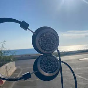 HeadPhones with a sea view The headphones are held to the left of the shot - at 90 degrees with a sea background.